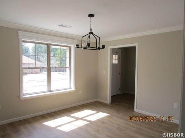 unfurnished dining area featuring ornamental molding, wood finished floors, visible vents, and baseboards