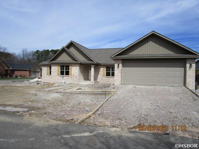 view of front of home with driveway, brick siding, and an attached garage