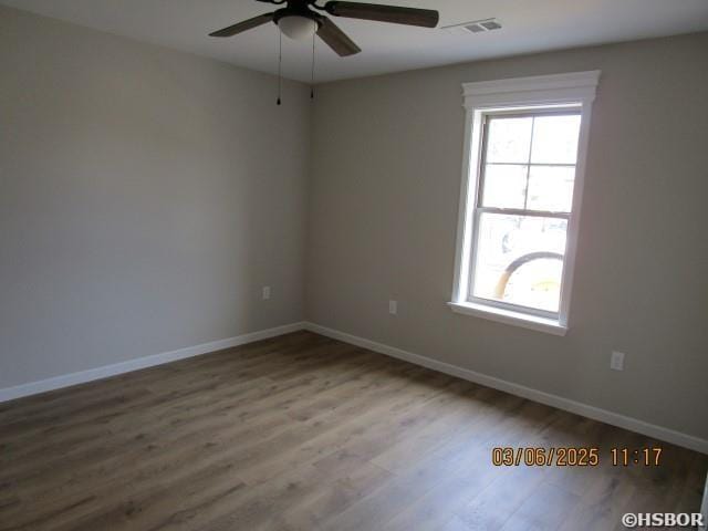 spare room with ceiling fan, wood finished floors, visible vents, and baseboards