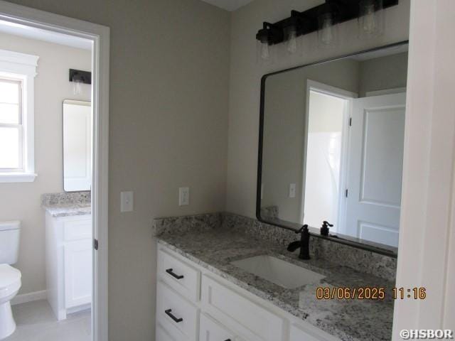 half bath with two vanities, a sink, and toilet