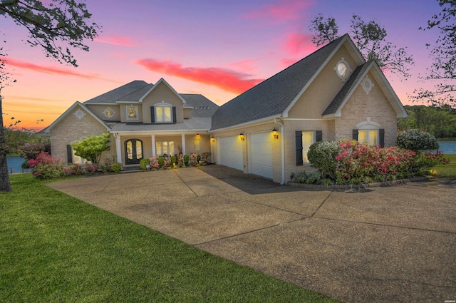 traditional-style home featuring driveway, stone siding, an attached garage, a yard, and brick siding