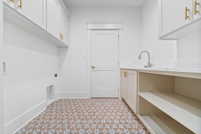 washroom with hookup for an electric dryer, a sink, baseboards, cabinet space, and light floors