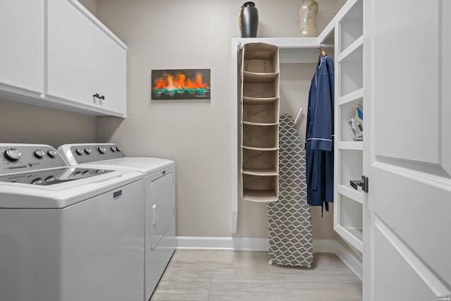 laundry area featuring washing machine and clothes dryer, cabinet space, and baseboards