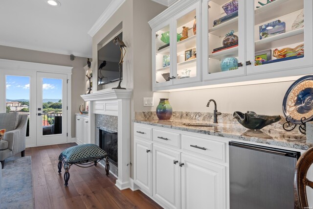 bar featuring a high end fireplace, ornamental molding, dark wood-type flooring, a sink, and recessed lighting