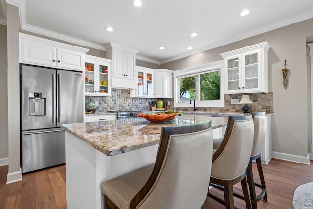 kitchen with high end refrigerator, a kitchen island, glass insert cabinets, and white cabinets