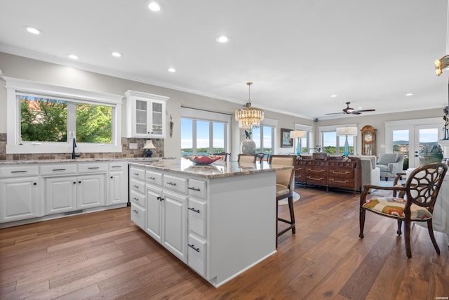 kitchen with glass insert cabinets, open floor plan, white cabinets, and decorative light fixtures