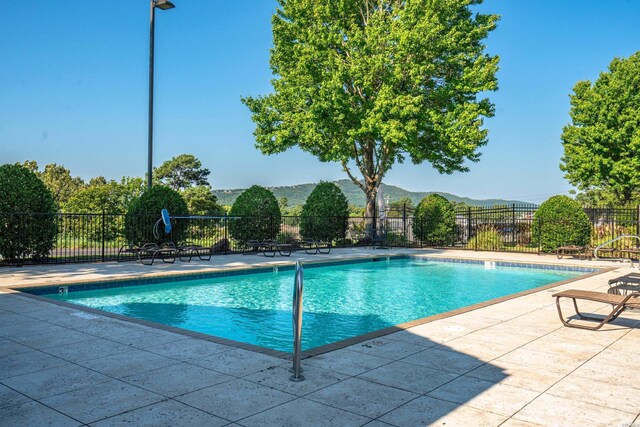 pool with a patio area, a mountain view, and fence