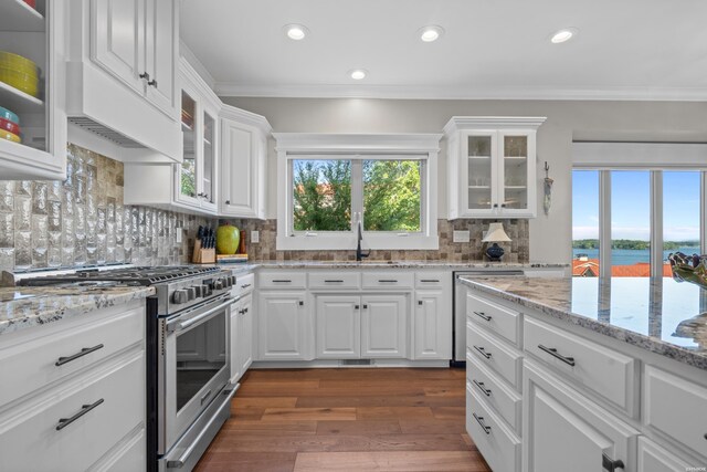 kitchen with stainless steel range, white cabinets, glass insert cabinets, a water view, and a sink