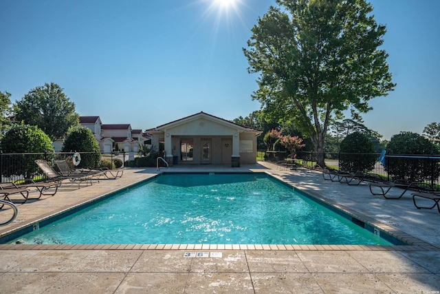 pool with a patio area and fence