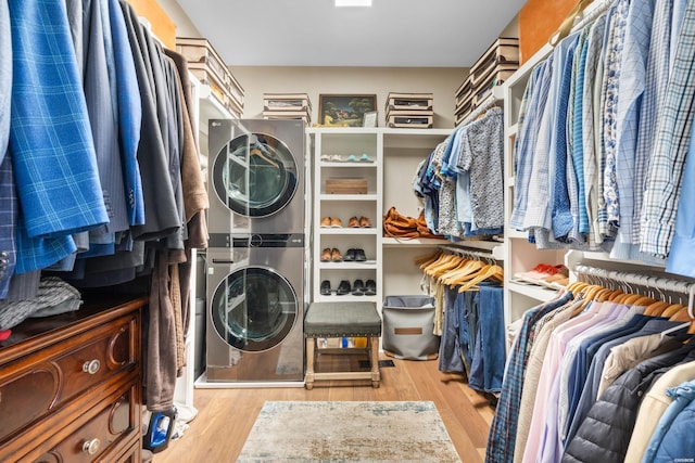 walk in closet with light wood-style flooring and stacked washer / drying machine