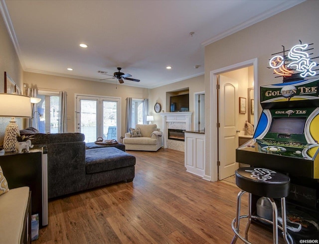 living room with a ceiling fan, wood finished floors, recessed lighting, a fireplace, and crown molding