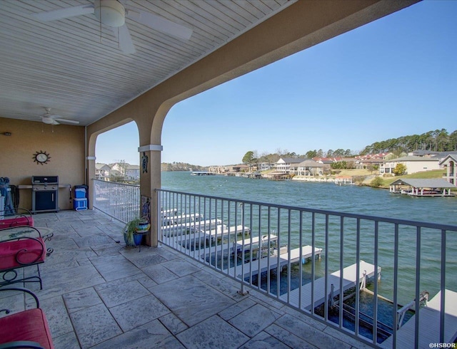 balcony with a residential view, a water view, and a ceiling fan