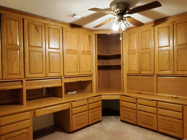 unfurnished office featuring light carpet, ceiling fan, visible vents, and built in desk