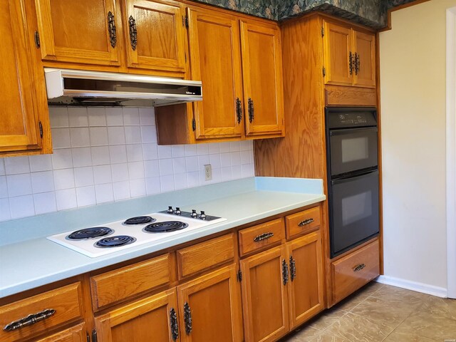 kitchen with tasteful backsplash, dobule oven black, brown cabinetry, white cooktop, and under cabinet range hood