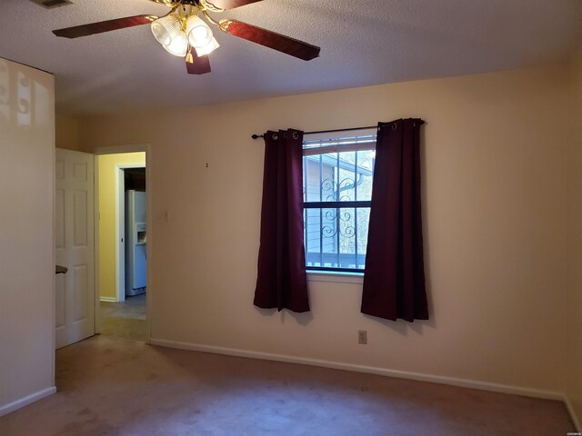 empty room with light carpet, ceiling fan, a textured ceiling, and baseboards