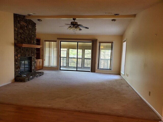 unfurnished living room featuring vaulted ceiling with beams, a fireplace, baseboards, and light colored carpet