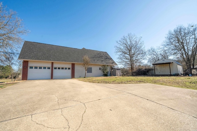 view of front of house featuring concrete driveway, roof with shingles, an attached garage, a front lawn, and brick siding