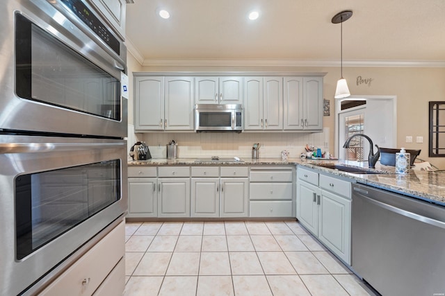 kitchen with appliances with stainless steel finishes, ornamental molding, a sink, and tasteful backsplash