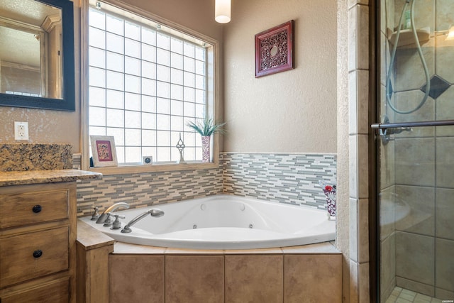 full bath featuring a whirlpool tub, a textured wall, a stall shower, and vanity