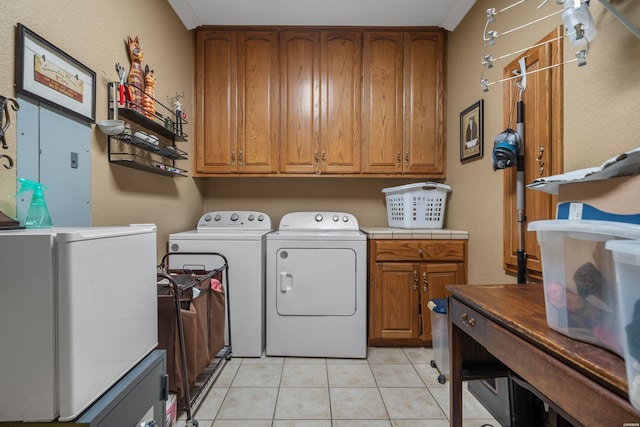 laundry room with light tile patterned floors, crown molding, separate washer and dryer, and cabinet space