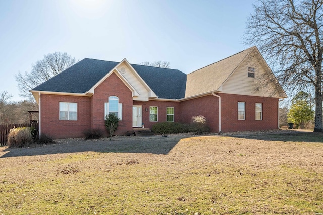 view of front of property with brick siding, a front yard, and fence