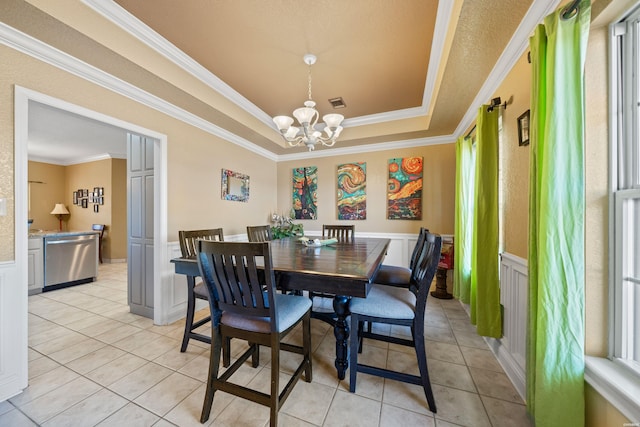 dining room with a wainscoted wall, light tile patterned floors, a raised ceiling, and an inviting chandelier