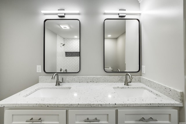 bathroom featuring a sink, a shower, and double vanity