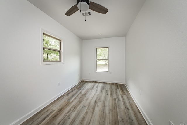 empty room featuring light wood-style floors, a wealth of natural light, and visible vents