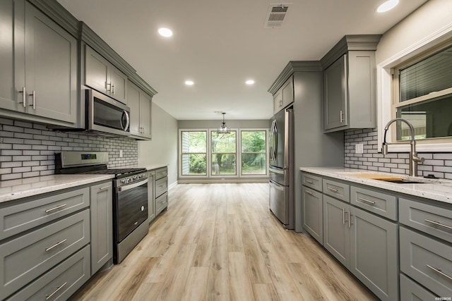kitchen featuring visible vents, a sink, appliances with stainless steel finishes, and gray cabinetry