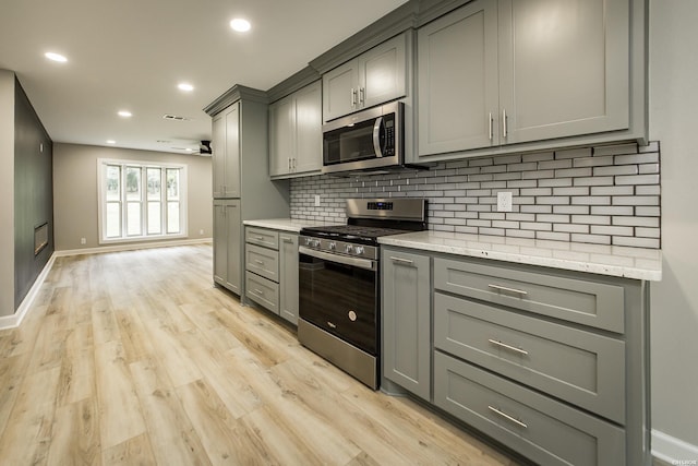 kitchen featuring gray cabinets, appliances with stainless steel finishes, and backsplash