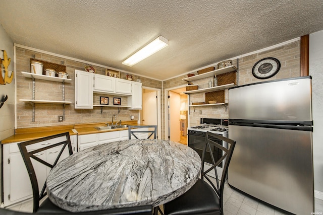 358 Buccaneer St, Hot Springs, AR 71913 - kitchen featuring open shelves, freestanding refrigerator, white range with gas stovetop, white cabinetry, and a textured ceiling