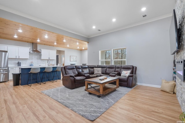 living room featuring light wood-style floors, visible vents, ornamental molding, and baseboards