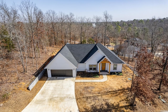 view of front of property featuring driveway, a forest view, and an attached garage