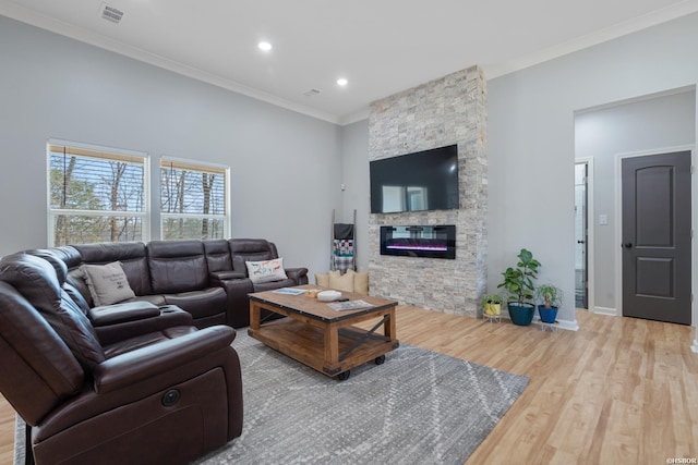 living room with a stone fireplace, wood finished floors, visible vents, baseboards, and crown molding