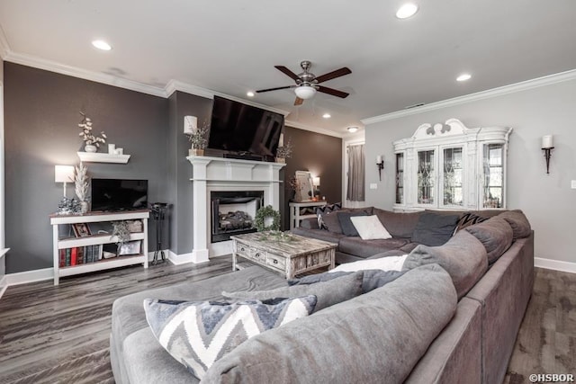 living area with baseboards, wood finished floors, crown molding, a fireplace, and recessed lighting