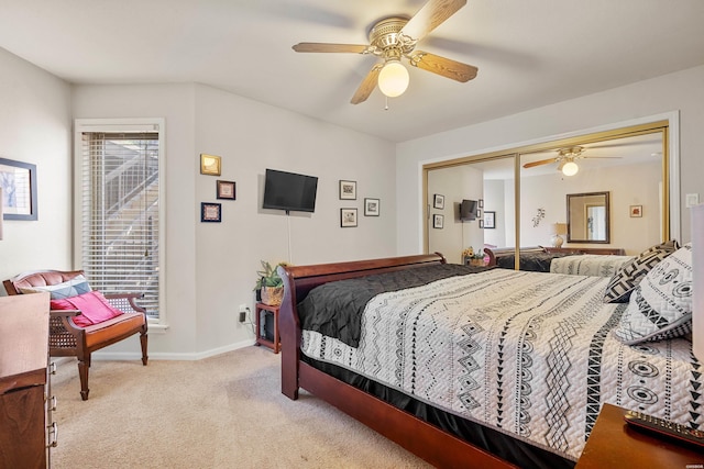 bedroom featuring light colored carpet, a ceiling fan, baseboards, and a closet