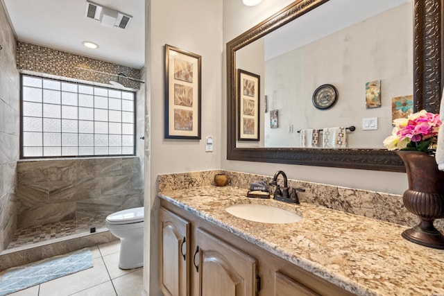 bathroom with vanity, tile patterned floors, a tile shower, and toilet