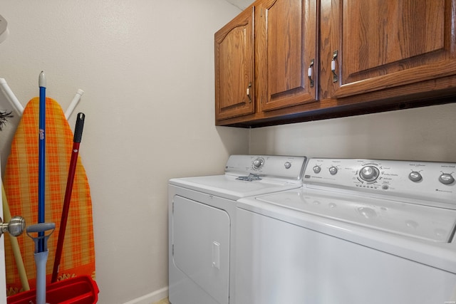 laundry area with baseboards, washer and clothes dryer, and cabinet space