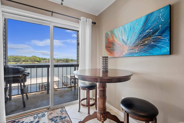 dining area featuring a water view, ornamental molding, baseboards, and tile patterned flooring