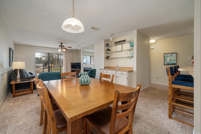 dining area with visible vents, a ceiling fan, light carpet, a textured ceiling, and baseboards