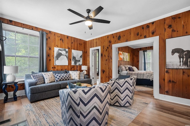 living room with ornamental molding, visible vents, a healthy amount of sunlight, and light wood-style flooring