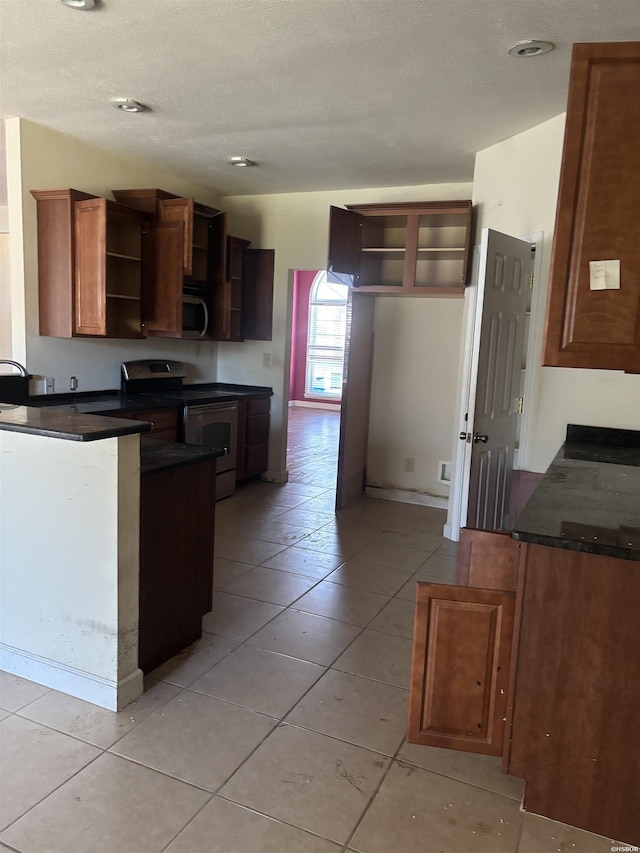 kitchen featuring light tile patterned floors, stainless steel appliances, dark countertops, open shelves, and a peninsula