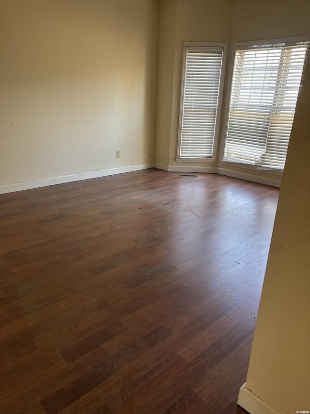 spare room with dark wood finished floors and baseboards