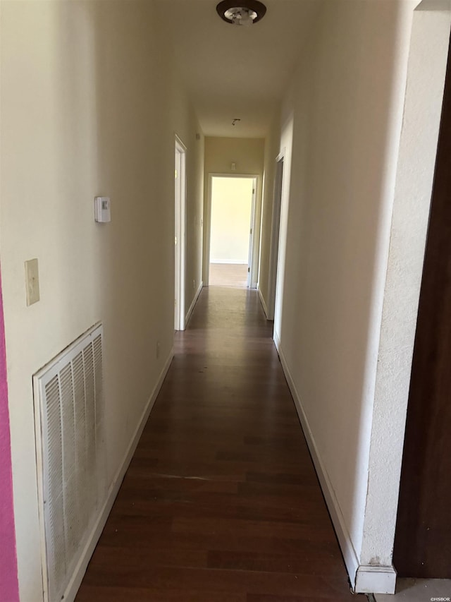 hall with baseboards, visible vents, and wood finished floors