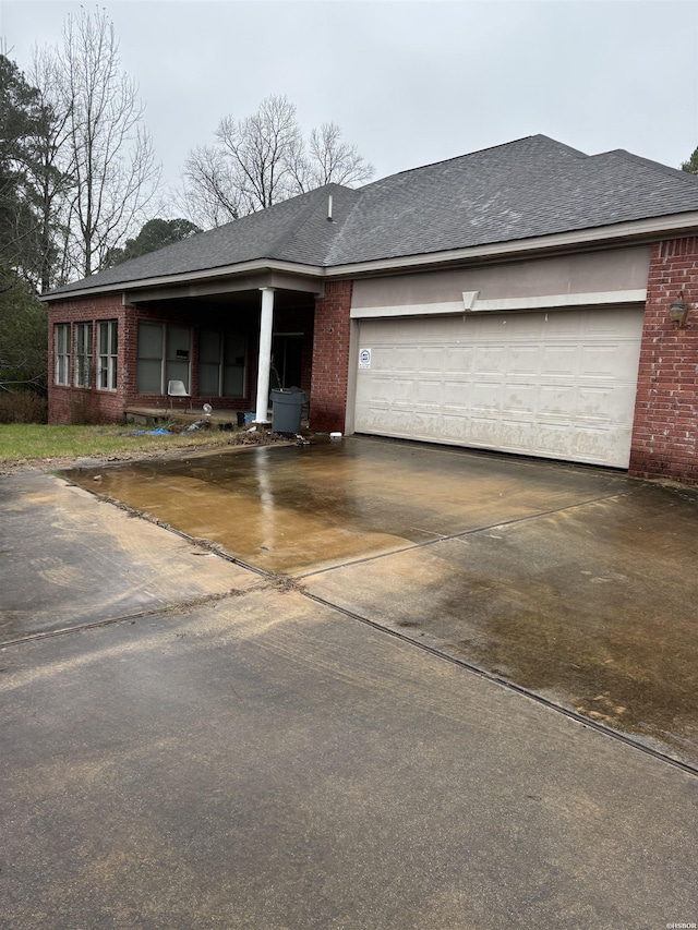 ranch-style house featuring a shingled roof, brick siding, driveway, and an attached garage