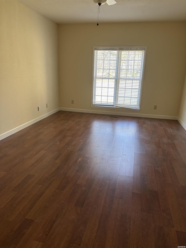 empty room with dark wood-style floors, ceiling fan, and baseboards