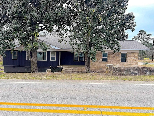 view of front facade featuring crawl space, stone siding, board and batten siding, and roof with shingles