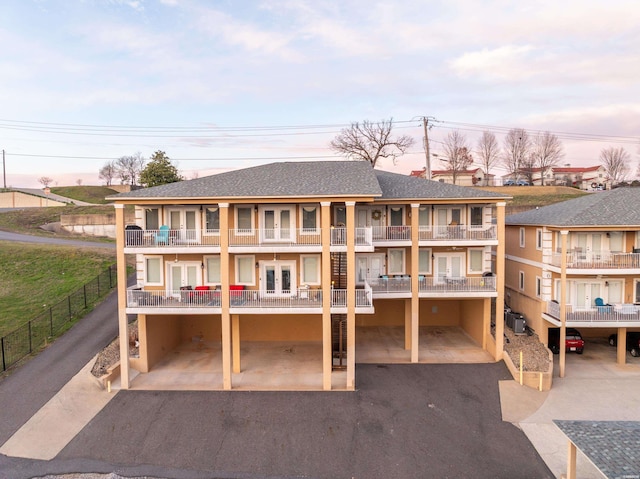 141 Central Ter Unit B, Hot Springs, AR 71913 - back of house at dusk with a balcony, central AC, driveway, roof with shingles, and stucco siding