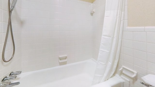 bathroom featuring toilet, a wainscoted wall, shower / bath combo with shower curtain, and tile walls