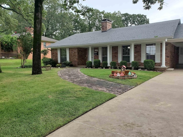 ranch-style house with a shingled roof, a chimney, a front lawn, and brick siding